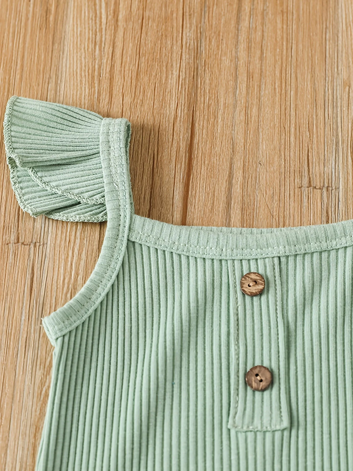 Close-up of ribbed baby bodysuit shoulder with wooden buttons