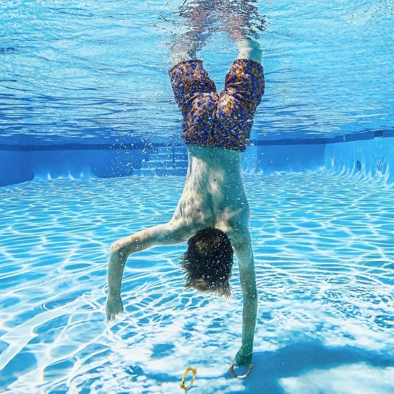 Child swimming underwater with diving rings